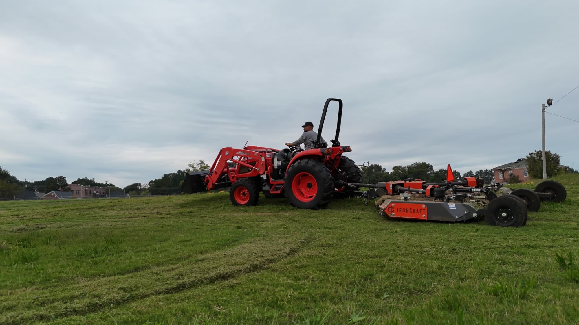 Kioti tractor pulling an IronCraft wide rotary cutter, bush hogging a grass field in Upstate SC
